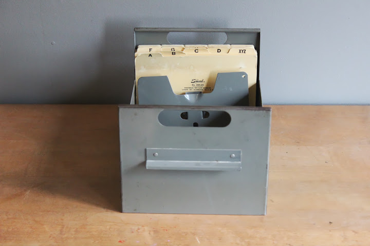 Gray metal file caddy with folders available for rent from www.momentarilyyours.com, $3.